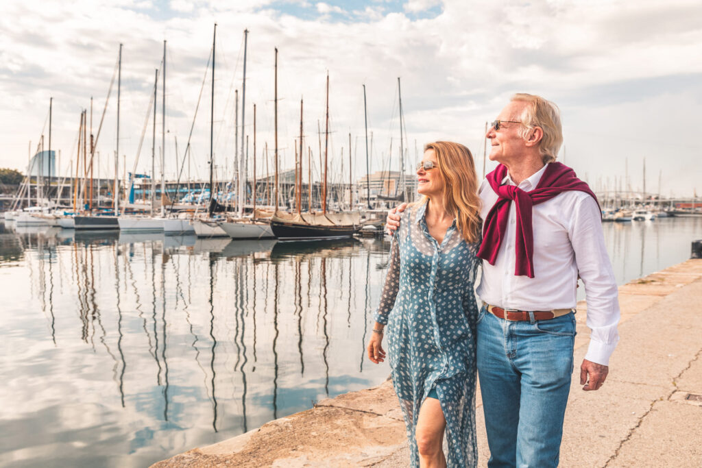 Couple retiring to spain enjoying their walk in the harbor full of boats